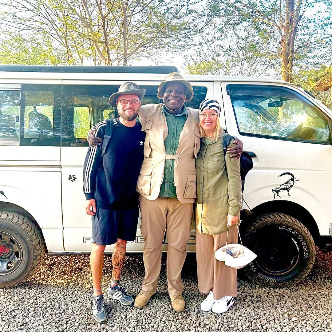 Safari guide and tourists standing in front of safari van before the evening game drive